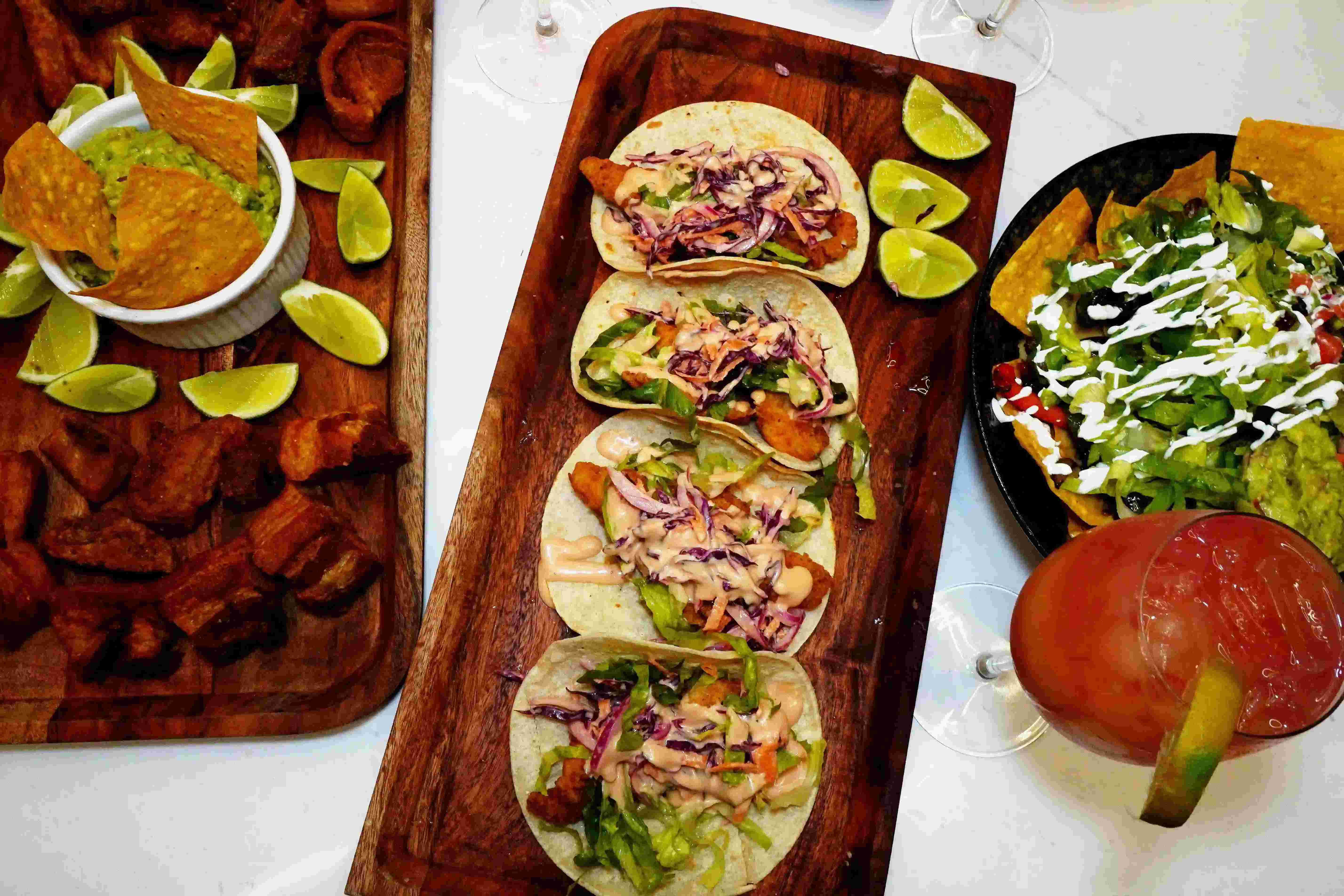 Delicious food photography featuring tacos, nachos, guacamole, and cocktails